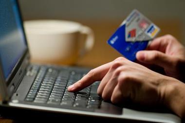 person typing into a computer holding a credit card